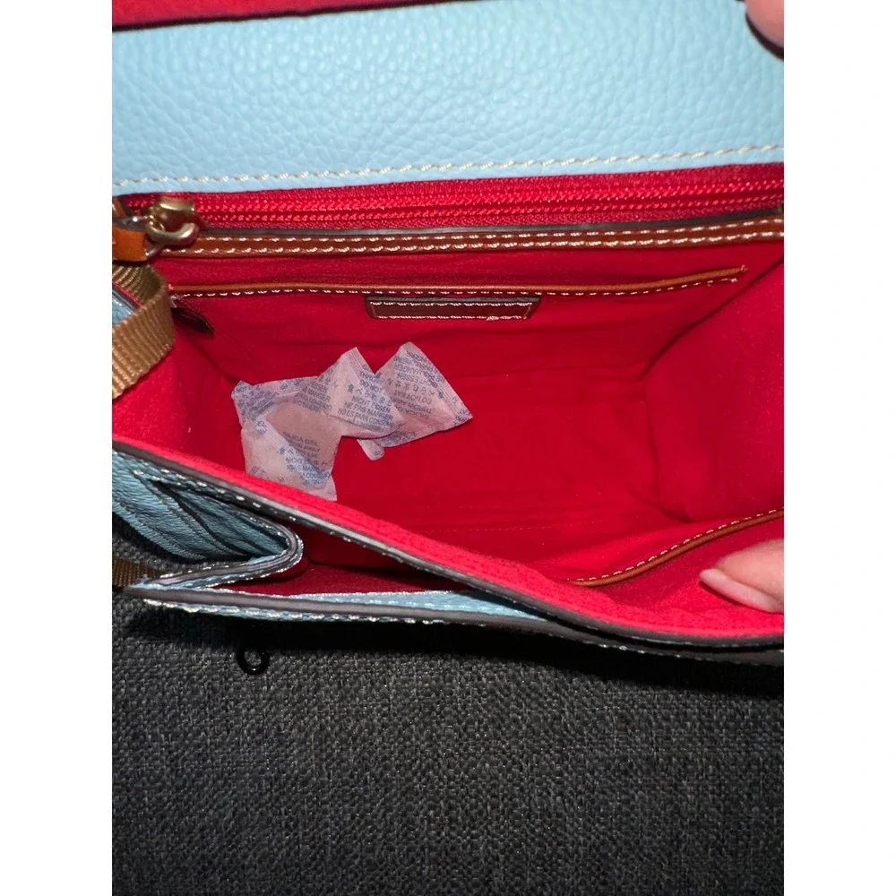 This is a Dooney & Bourke Pebble Grain East/West Flap Crossbody in a light blue